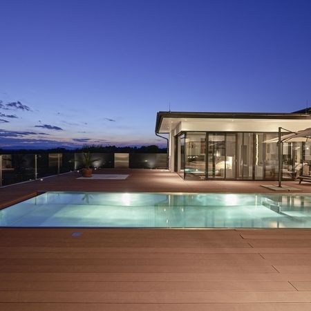 Großer Pool vor einem modernen Haus in der Dunkelheit