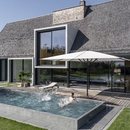 Kinder spielen in einem Pool vor einem Haus