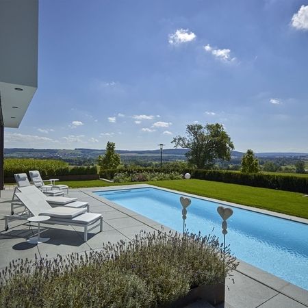 Modernes Ambiente mit einem Pool und Liegen