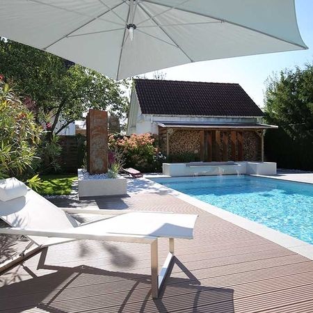 Großer Pool vor einem modernem Haus und einer Liege