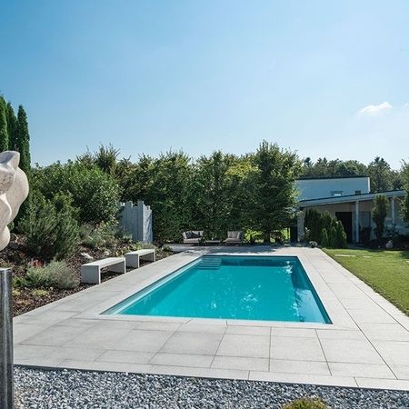 Moderner Pool vor einem Haus und einer Statue im Vordergrund