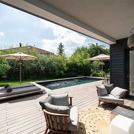 Moderner Pool vor einem Haus mit einem Sonnenschirm
