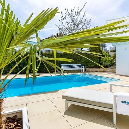 Moderner Pool vor einem weißen Haus und einer Palme