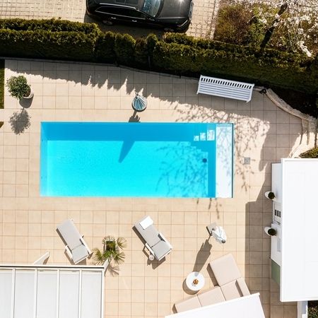 Moderner Pool vor einem weißen Haus von oben