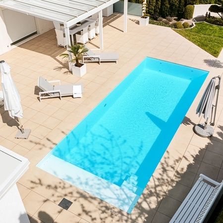 Moderner Pool vor einem weißen Haus von oben