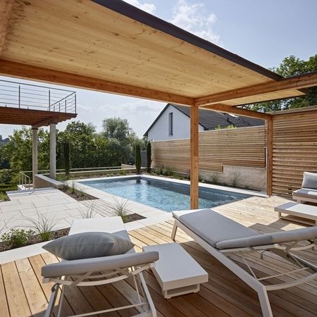 Ein Pool aus Edelstahlbecken und Holzelementen mit Sitzmöglichkeiten