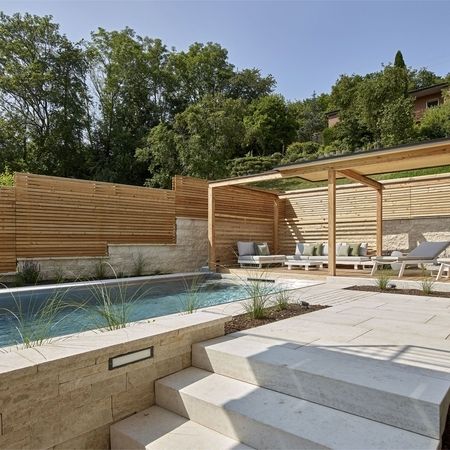 Ein Pool aus Edelstahlbecken und Holzelementen mit Sitzmöglichkeiten