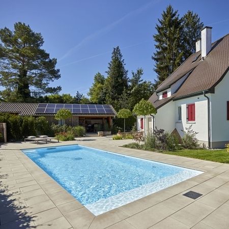 Ein Haus und ein Pool mit Liegen