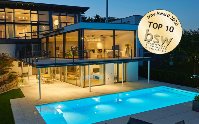 Moderner Pool vor einem großen Haus bei Nacht