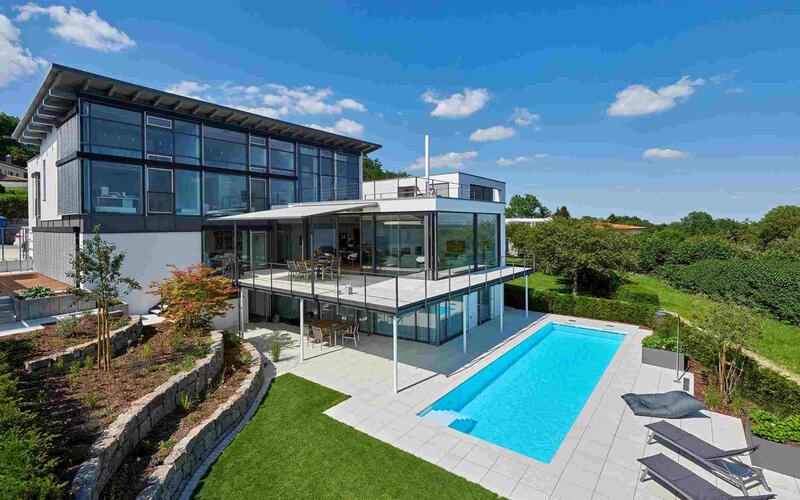 Großer Pool im Garten vor einem modernen Haus